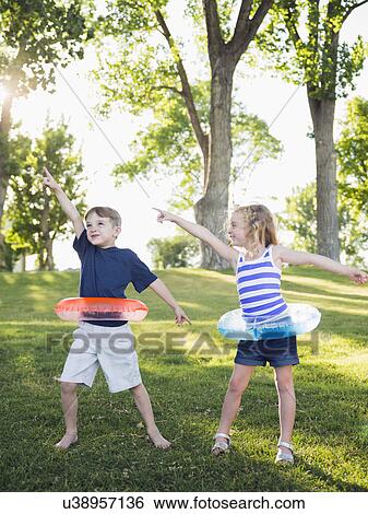 Two kids (4-5, 6-7) playing with inflatable rings in park View Large Photo Image Stock Photograph - Two kids (4-5, 6-7) playing with inflatable rings in park . Fotosearch