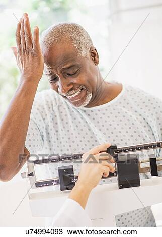 Stock Image - Upset man on weight scale. Fotosearch