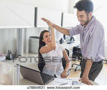 Stock Image - Woman and man giving high five to each other. Fotosearch