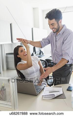Stock Photo - Woman and man giving high five to each other. Fotosearch