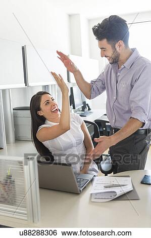 Stock Photograph - Woman and man giving high five to each other. Fotosearch