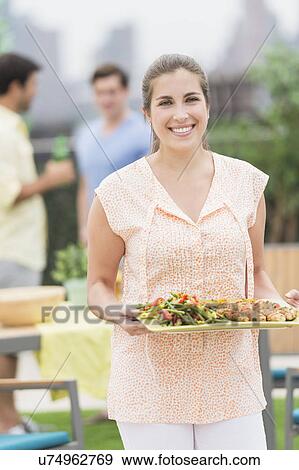 Woman carrying tray with food in garden View Large Photo Image Stock Photo - Woman carrying tray with food in garden. Fotosearch