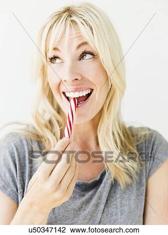 Woman eating candy cane, studio shot View Large Photo Image Stock Image - Woman eating candy cane, studio shot. Fotosearch