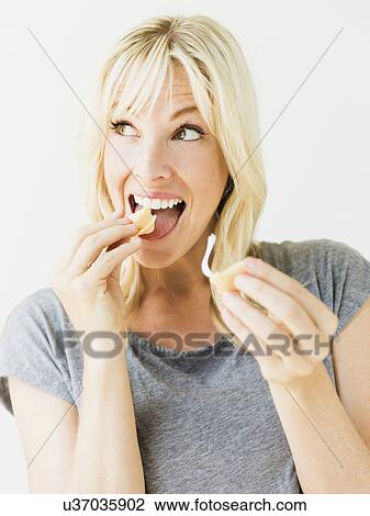 Woman eating fortune cookie, studio shot View Large Photo Image Stock Image - Woman eating fortune cookie, studio shot. Fotosearch