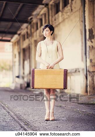 Woman in dress holding suitcase at train station View Large Photo Image Picture - Woman in dress holding suitcase at train station. Fotosearch