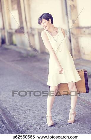 Woman in dress holding suitcase at train station View Large Photo Image Stock Photography - Woman in dress holding suitcase at train station. Fotosearch