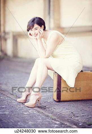 Woman in dress sitting on suitcase at train station View Large Photo Image Stock Image - Woman in dress sitting on suitcase at train station. Fotosearch