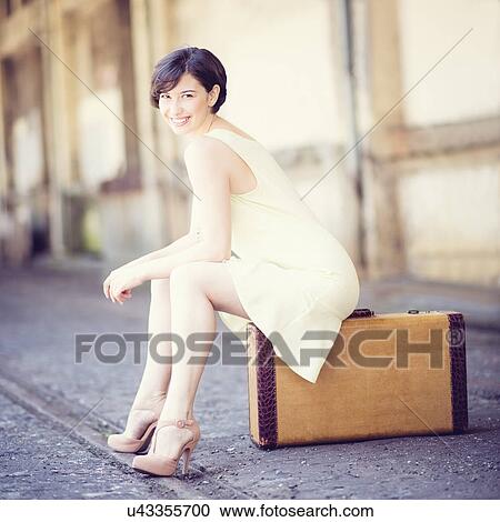 Woman in dress sitting on suitcase at train station View Large Photo Image Stock Image - Woman in dress sitting on suitcase at train station. Fotosearch