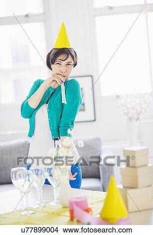 Woman in party hat standing behind table at home View Large Photo Image Picture - Woman in party hat standing behind table at home. Fotosearch