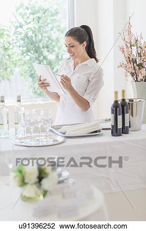 Stock Image - Woman preparing table in restaurant. Fotosearch