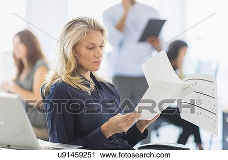 Woman reading at desk in office View Large Photo Image Stock Image - Woman reading at desk in office. Fotosearch