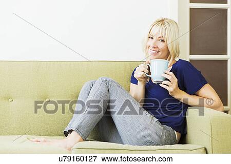 Woman relaxing on sofa and drinking coffee View Large Photo Image Stock Photo - Woman relaxing on sofa and drinking coffee. Fotosearch