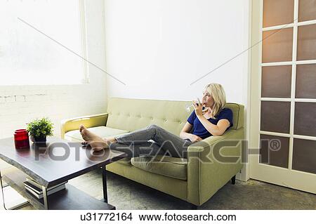 Woman relaxing on sofa and drinking wine View Large Photo Image Picture - Woman relaxing on sofa and drinking wine. Fotosearch