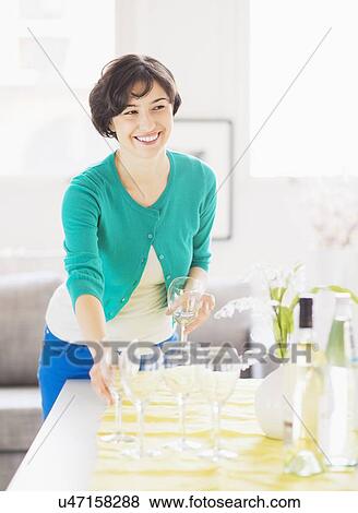 Stock Photo - Woman setting table at home. Fotosearch