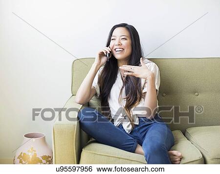 Woman sitting on sofa and talking on phone View Large Photo Image Stock Photograph - Woman sitting on sofa and talking on phone. Fotosearch