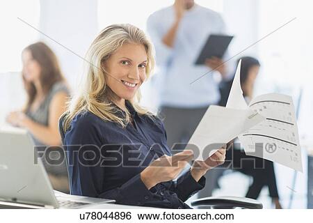 Woman smiling at desk in office View Large Photo Image Stock Photograph - Woman smiling at desk in office. Fotosearch