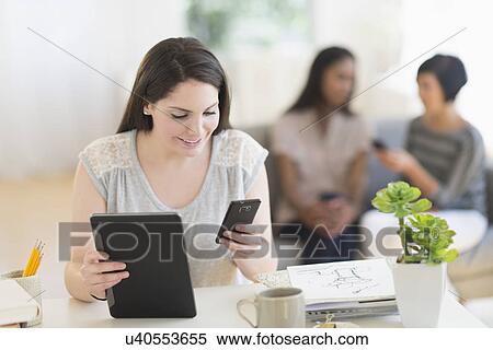 Stock Photography - Woman using digital tablet and mobile phone. Fotosearch