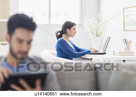 Woman using laptop and man using digital tablet at home View Large Photo Image Stock Image - Woman using laptop and man using digital tablet at home. Fotosearch