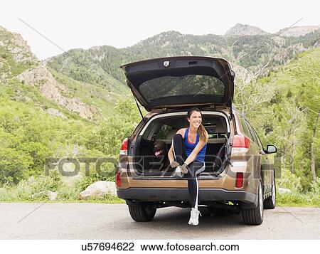Woman wearing sportswear sitting at car trunk with dog View Large Photo Image Stock Image - Woman wearing sportswear sitting at car trunk with dog. Fotosearch