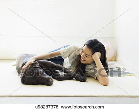 Woman with dog lying on floor View Large Photo Image Stock Photo - Woman with dog lying on floor. Fotosearch