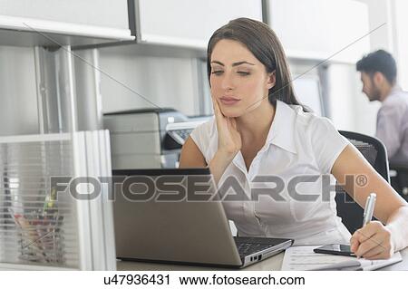 Woman working in office, man in background View Large Photo Image Stock Image - Woman working in office, man in background. Fotosearch