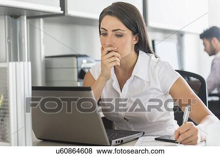 Woman working in office, man in background View Large Photo Image Stock Photo - Woman working in office, man in background. Fotosearch