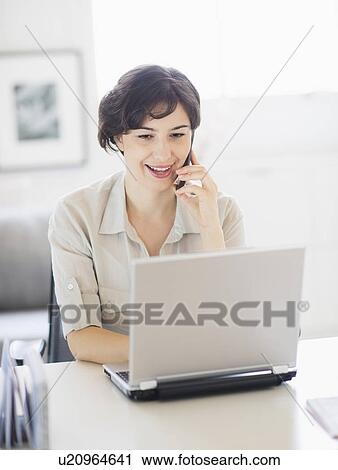 Woman working on laptop and talking on phone View Large Photo Image Stock Image - Woman working on laptop and talking on phone . Fotosearch