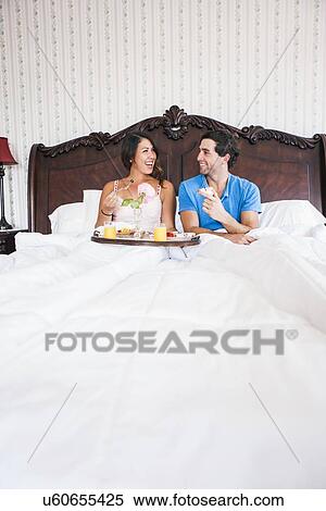 Young couple eating breakfast in bed in hotel room View Large Photo Image Stock Photography - Young couple eating breakfast in bed in hotel room. Fotosearch