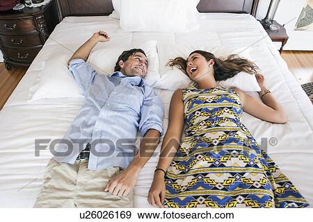 Stock Photo - Young couple lying on bad in hotel room. Fotosearch