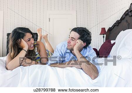 Young couple lying on bad in hotel room View Large Photo Image Stock Photo - Young couple lying on bad in hotel room. Fotosearch