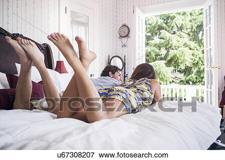 Young couple lying on bad in hotel room View Large Photo Image Stock Photo - Young couple lying on bad in hotel room. Fotosearch