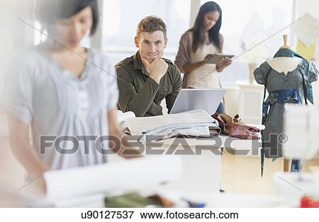 Stock Photo - Young fashion designers working in studio. Fotosearch