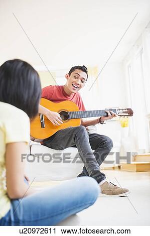 Young man playing guitar and singing, woman listening View Large Photo Image Stock Image - Young man playing guitar and singing, woman listening. Fotosearch
