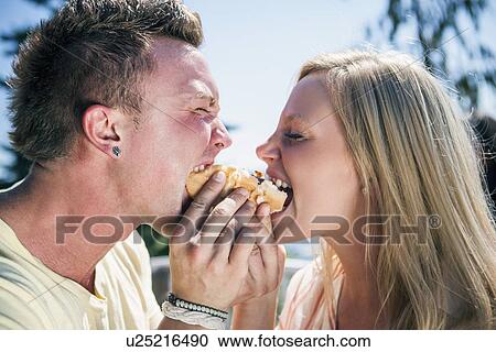 Young people eating one hot dog View Large Photo Image Stock Image - Young people eating one hot dog. Fotosearch
