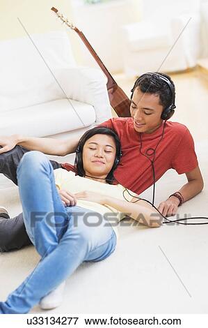 Young woman and man listening music with headphones on View Large Photo Image Stock Photo - Young woman and man listening music with headphones on. Fotosearch