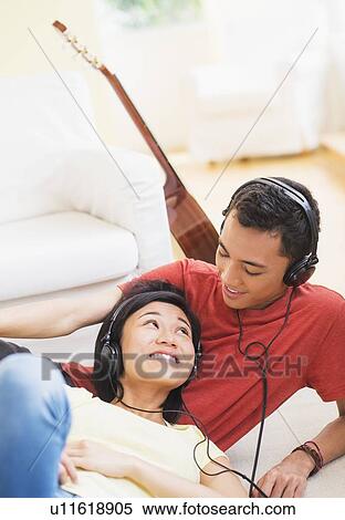 Young woman and man listening music with headphones on View Large Photo Image Stock Photography - Young woman and man listening music with headphones on. Fotosearch