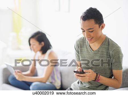 Young woman and young man sitting on sofa View Large Photo Image Stock Photo - Young woman and young man sitting on sofa. Fotosearch