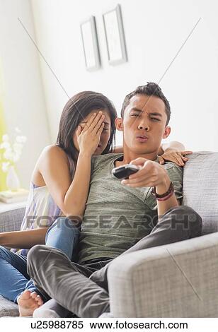 Stock Photography - Young woman and young man sitting on sofa. Fotosearch