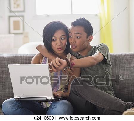 Stock Image - Young woman and young man using laptop. Fotosearch