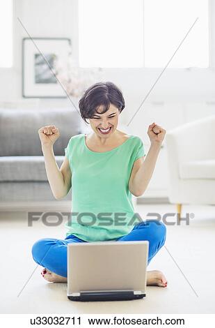 Young woman cheering in front of laptop View Large Photo Image Stock Image - Young woman cheering in front of laptop. Fotosearch