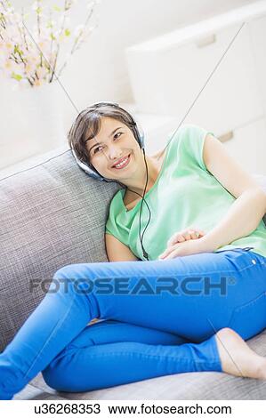 Stock Image - Young woman listening to music at home. Fotosearch