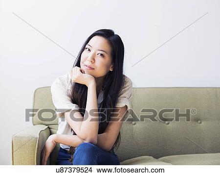 Young woman sitting on sofa View Large Photo Image Picture - Young woman sitting on sofa. Fotosearch