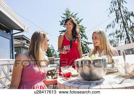 Stock Image - Young women enjoying outdoor meal. Fotosearch