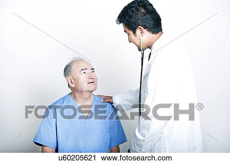 Stock Image - A young Asian Doctor comforting a Senior adult patient. Fotosearch