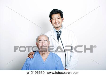 Stock Photo - A young Asian Doctor with his hand on the shoulder of a Senior adult patient. Fotosearch