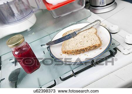 Stock Image - Baked bread and jam bottle on kitchen counter. Fotosearch
