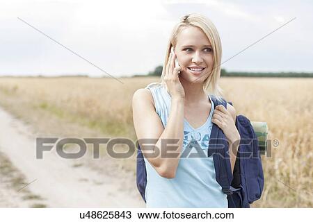 Beautiful female hiker using mobile phone on field View Large Photo Image Stock Image - Beautiful female hiker using mobile phone on field. Fotosearch