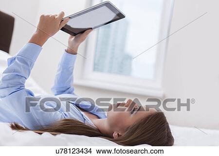 Beautiful woman using tablet computer on her bed View Large Photo Image Picture - Beautiful woman using tablet computer on her bed. Fotosearch