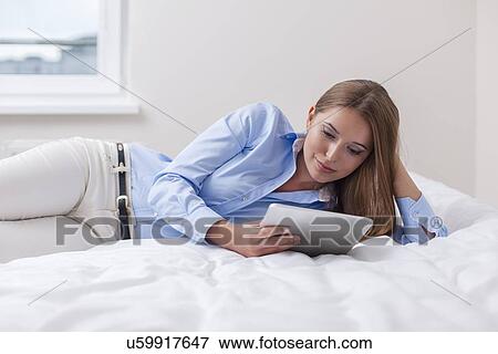 Beautiful woman using tablet computer on her bed View Large Photo Image Stock Photo - Beautiful woman using tablet computer on her bed. Fotosearch