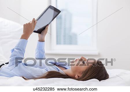 Beautiful woman using tablet computer on her bed View Large Photo Image Stock Photography - Beautiful woman using tablet computer on her bed. Fotosearch